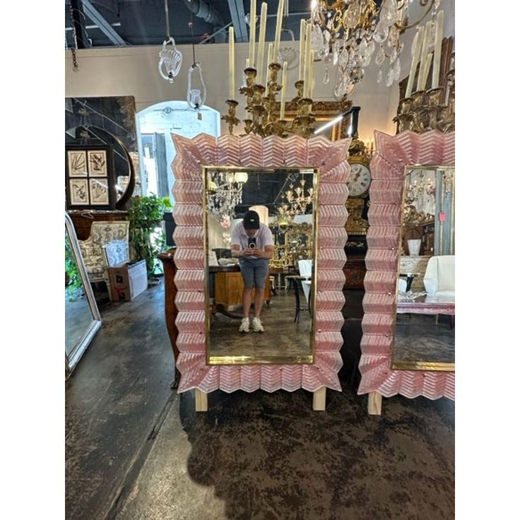 a pink and white mirror sitting on top of a table next to a chandelier