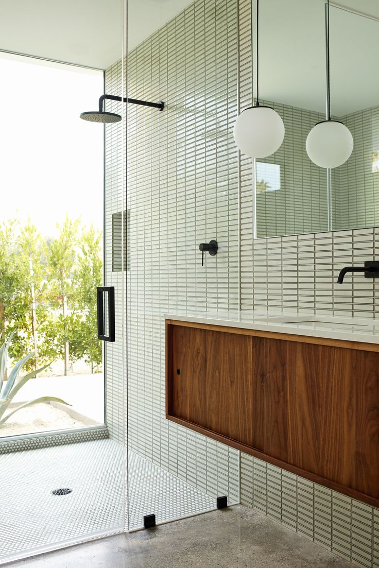 a bathroom with a sink, mirror and bathtub next to a glass door that leads outside