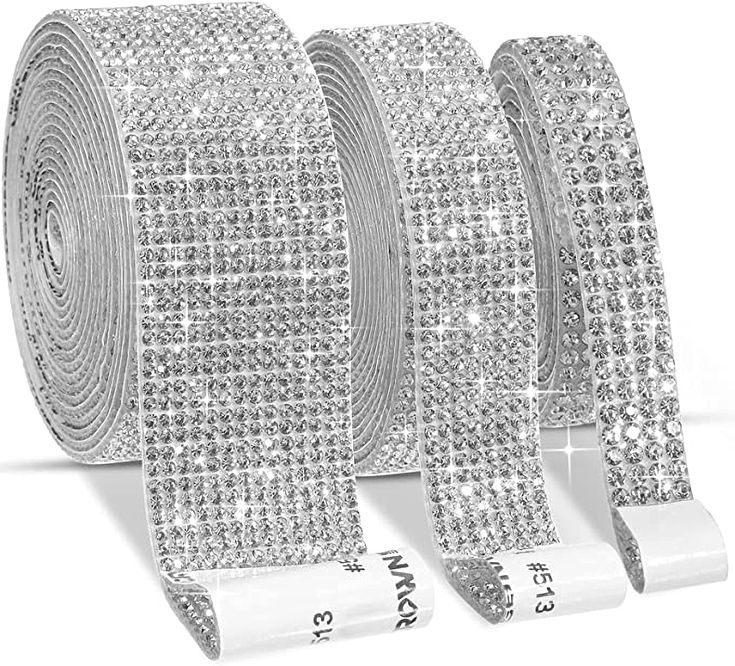 three rolls of silver sequinized glitter ribbon with white ribbons on each side and one roll