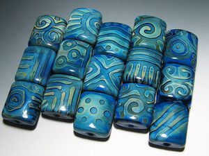 blue glass beads with swirls and dots on them are lined up in a row