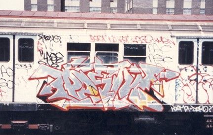 a train car with graffiti on it parked in front of a building that has many windows