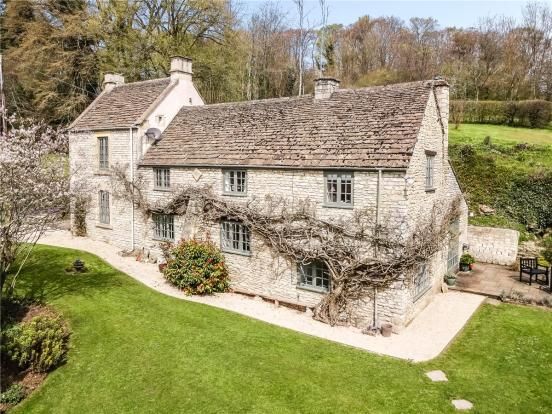 an aerial view of a stone house in the country side with green grass and trees