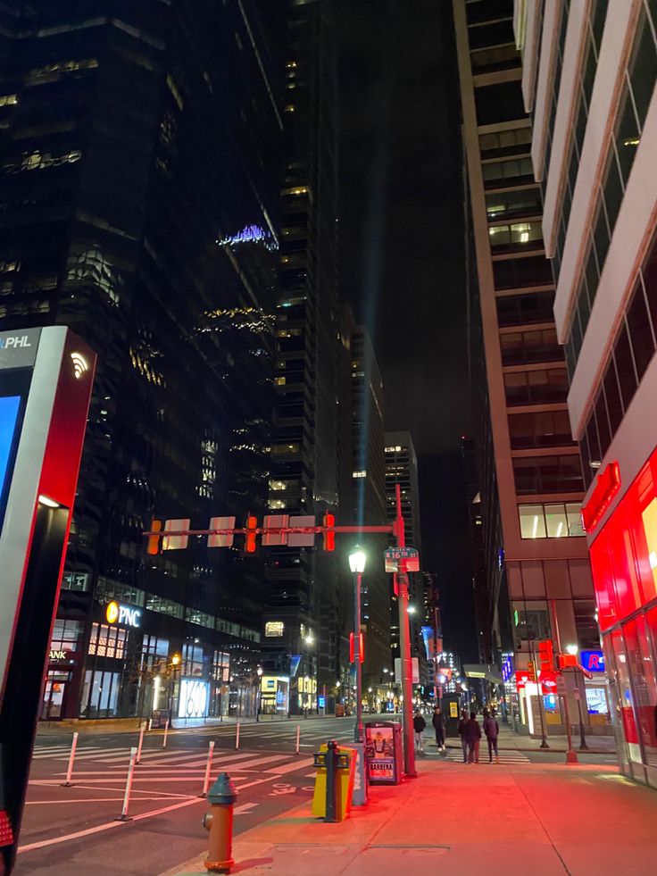 a city street at night with tall buildings in the background