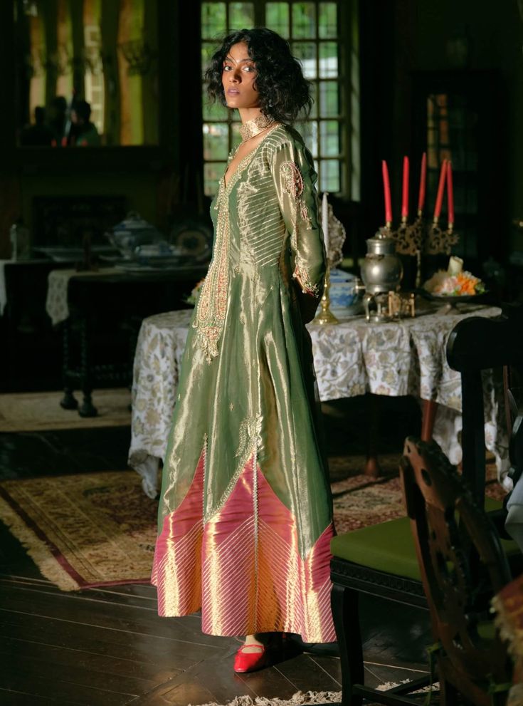 Immerse yourself in timeless elegance with this classic kalidar anarkali set, meticulously crafted from emerald green silk zari tissue and jacquard silk banarasi. Featuring jharokha-inspired panels and intricately embroidered paisley patterns in zari and zardozi, the design is further enhanced with dabka, sequins, pearls, and gota texturing for rich depth. The look is completed with a shimmering green tissue dupatta, adorned with matching jharokha-inspired panels, paisley embroidery, and sequin and pearl tassels, creating an elegantly defined silhouette. Tissue Anarkali, Kalidar Anarkali, Tissue Dupatta, Pearl Tassels, Paisley Embroidery, Green Silk, Paisley Pattern, Anarkali, Emerald Green