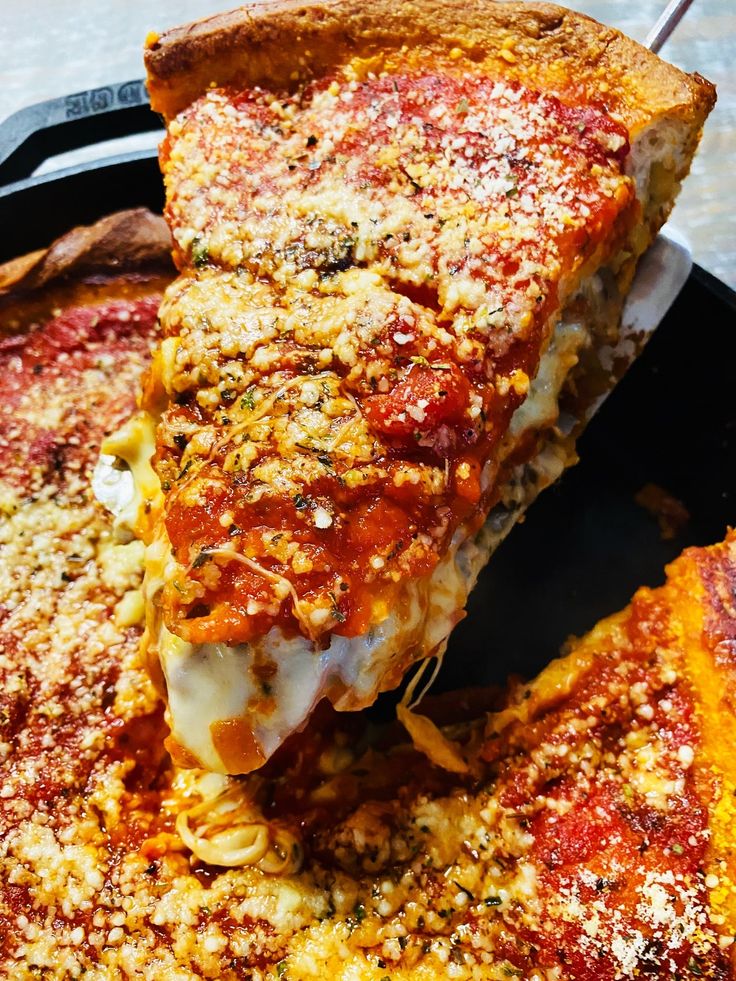 a piece of deep dish pizza with cheese and sauce on it is being held up by a spatula