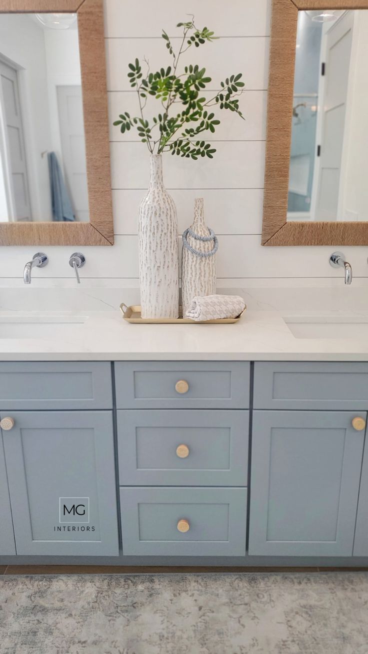 a bathroom with two sinks, mirrors and a vase filled with flowers on the counter