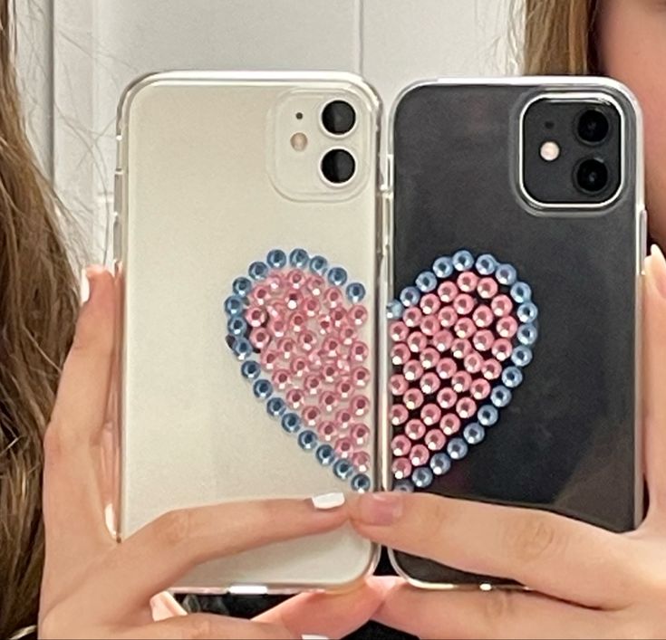 a woman holding up two cell phones with hearts on the front and back covers in different colors