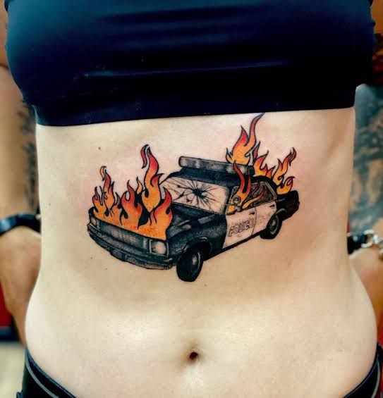 a woman's stomach with a police car on it and flames coming out of the back