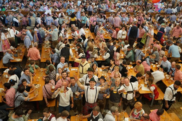 a large group of people sitting at tables in a room with wooden floors and walls