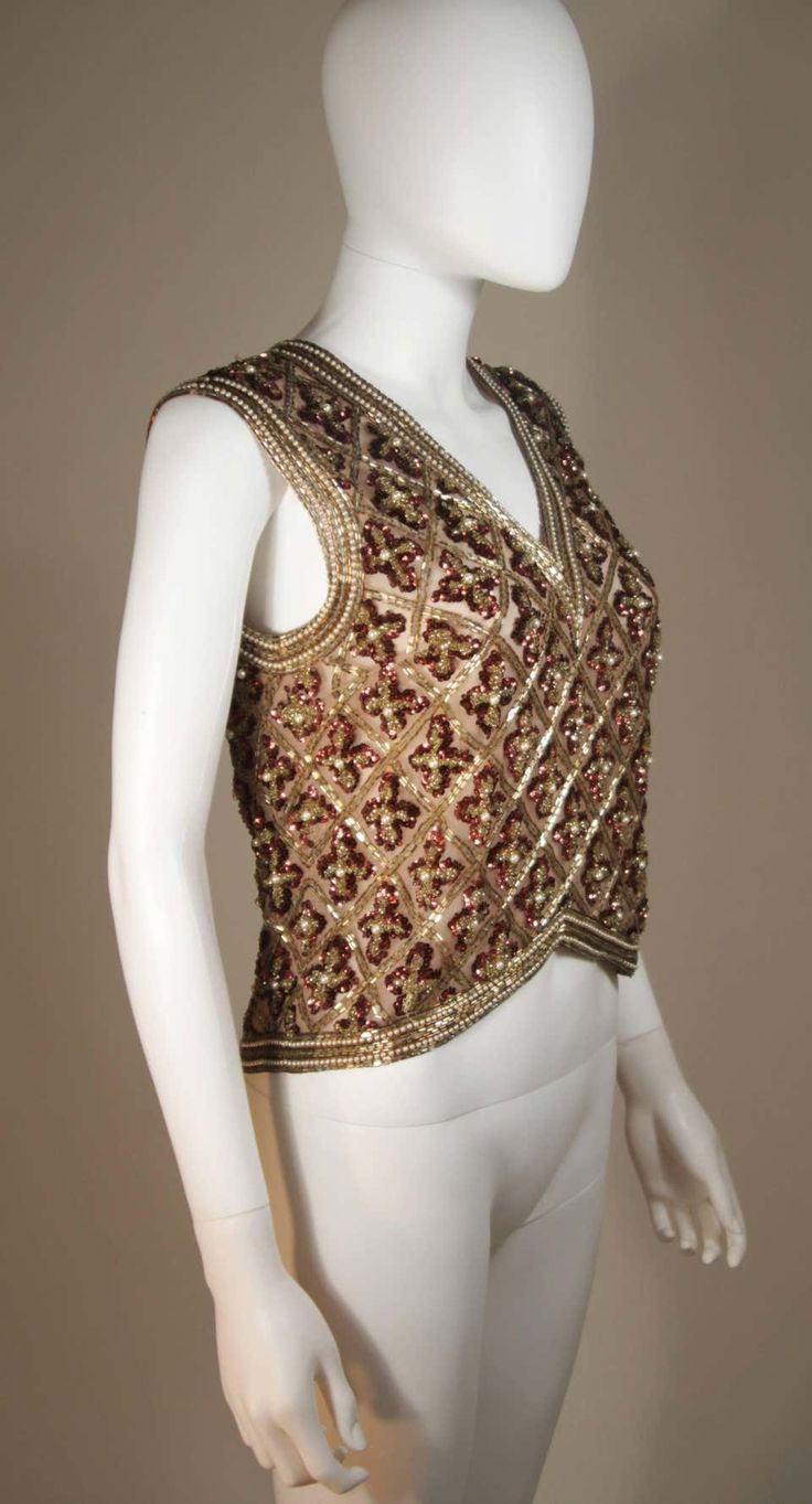 For Sale on 1stDibs - This Galanos blouse is composed of a beaded and sequin appliqued silk, in gold and burgundy hues. The top features a 3-dimensional beading technique. There Luxury Embellished Tops For Formal Occasions, Luxury Embellished Formal Top, Luxury Embellished Fitted Top, Traditional Fitted Evening Tops, Festive Hand Embellished Tops For Reception, Fitted Hand Embellished Tops For Festive Occasions, Festive Fitted Hand Embellished Tops, Silk Embroidered Evening Tops, Glamorous Hand Embellished Tops For Party