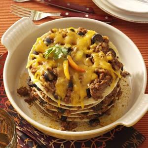 a stack of food sitting on top of a white plate next to a fork and knife