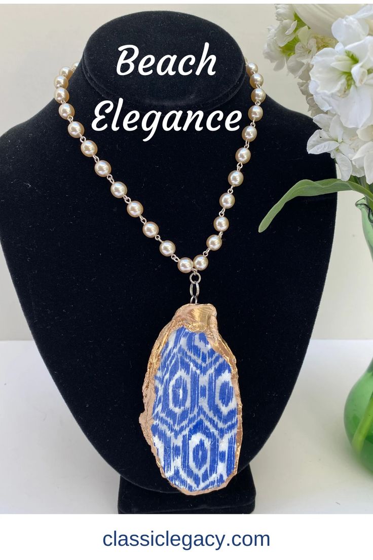 Our oyster shell necklace features a blue and white ikat design that has a gold leaf border.   The back side is also gold leaf.   The neck chain is a 15" pearl link lin with a silver toggle closure.   This necklace is one of a kind since we use real oyster shells.  The shell shown is 4" long and 2" wide.   The oyster shells in this design will be very similar to this.  Know that you are purchasing a unique hand-made gift. Bohemian Blue Necklace With Pearl Chain, Lake Gifts, Leaf Border, Ikat Design, Great Wedding Gifts, Shell Ring, Oyster Shells, Neck Chain, Shell Art