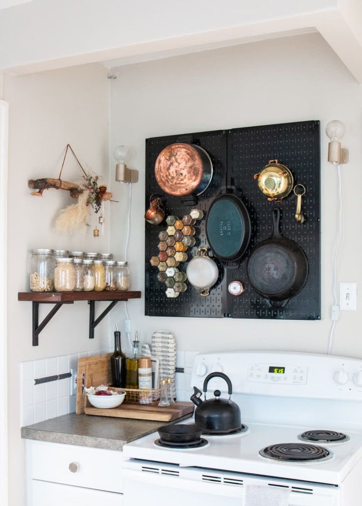 a stove top oven sitting inside of a kitchen next to a wall mounted pot rack