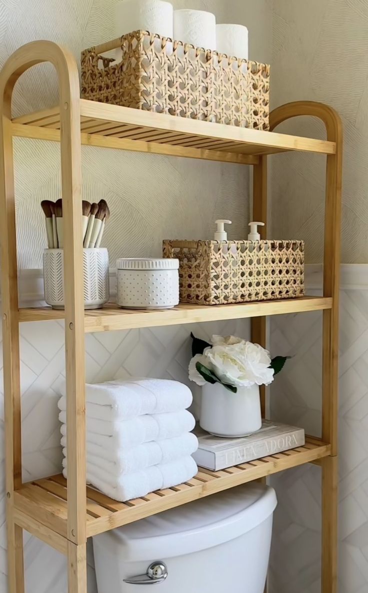 a wooden shelf filled with lots of white towels and toilet paper next to a trash can