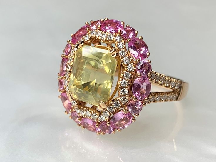 Yellow Sapphire Ring, Yellow Sapphire Engagement Ring, Pink Halo Ring, Gemstone Engagement, Sapphire Statement Ring, Sapphire Cocktail Ring A one -of- a kind luxurious, colorful pastel sapphire ring featuring a bright and glowing 4.17 carat emerald cut yellow sapphire surrounded by 1.16 carats of vibrant oval pink sapphires and 0.40 carats of white diamonds set with expert craftsmanship in 18k rose / pink gold. This is an ideal gift for all of life's milestone such as: alternate engagement ring, Pink Halo Ring, Yellow Sapphire Engagement Ring, Dainty Earrings Studs, Yellow Sapphire Ring Engagement, Antique Emerald Ring, Sapphire Engagement Ring Halo, Pink Sapphire Diamond Ring, Engagement Ring Sapphire, Yellow Sapphire Ring