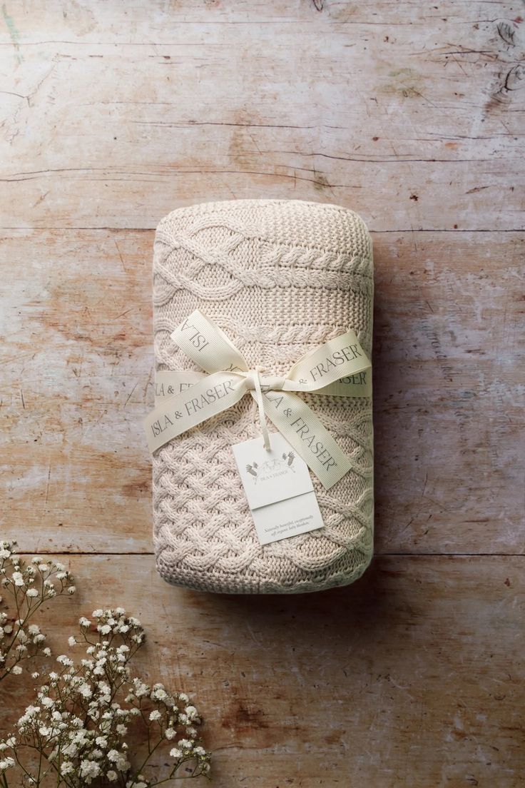 a wrapped gift sitting on top of a wooden table next to baby's breath