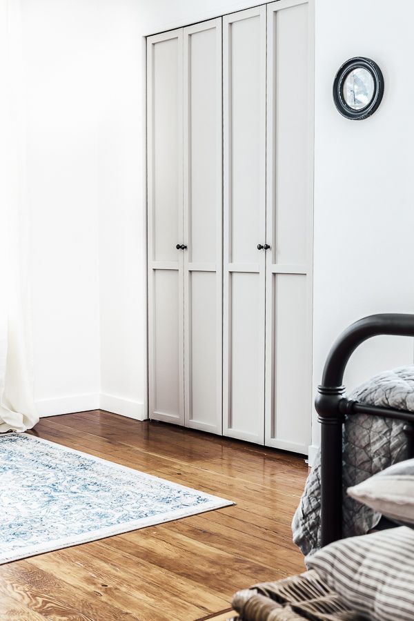 a bedroom with white closets and wood flooring next to a blue area rug