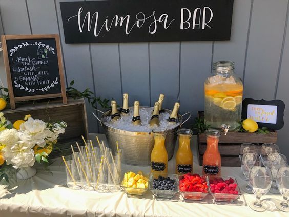 a table topped with drinks and fruit next to a sign that says mimosa bar