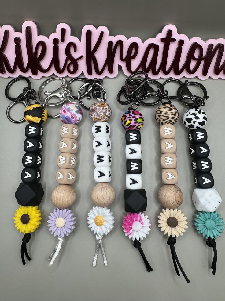 a bunch of key chains that have flowers on them and the words kiki's creations