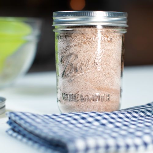 a glass jar filled with sand next to a blue and white checkered cloth on top of a table