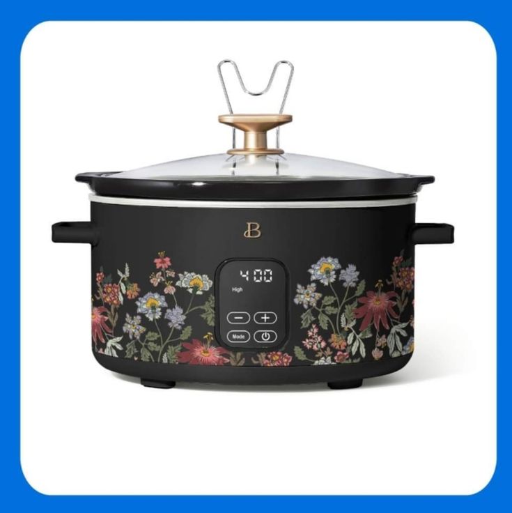 an electric crock pot with flowers on the side and a metal lid, in front of a blue background