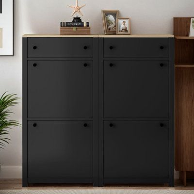 a black cabinet with three doors and two pictures on top, in front of a white wall