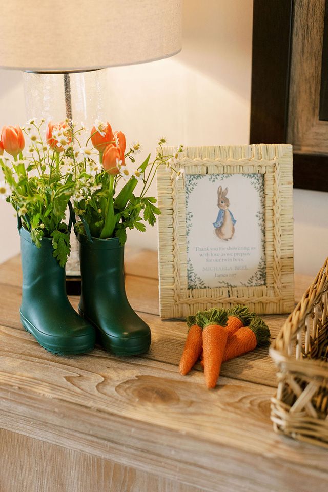 some carrots and flowers are sitting on a table next to a photo frame with a bunny