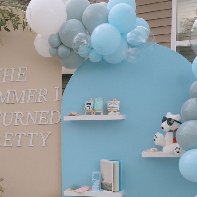 a room with blue and white balloons hanging from the ceiling, shelves filled with toys