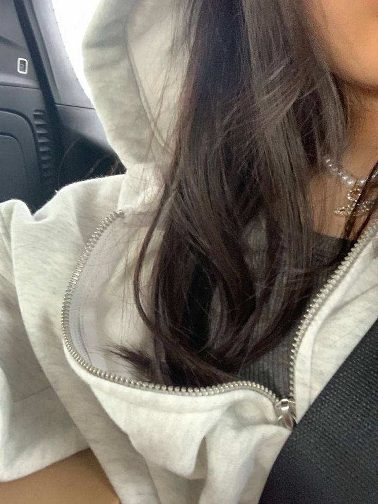 a woman wearing a hoodie sitting in the back seat of a car