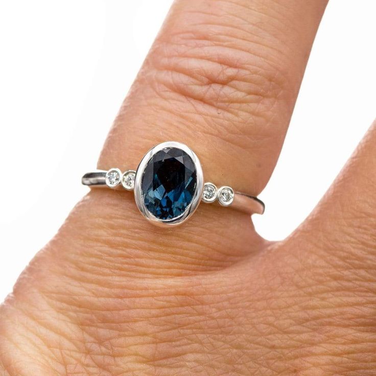 Brooklynn Ring Mounting - Accented low profile bezel set sterling silver ring with bezel set oval London Blue Topaz and moissanite side stones. ♥ Great for those who are active, minimalist and "hard" on their jewelry. This low-profile bezel setting sits as low to the finger as possible. The full bezel settings protect the gemstones. ♥ It is best worn by itself or stacked with curved or pointed nesting bands. Shown here with a custom-fitted ring (sold separately). Topaz Specifications: Size: 8x6 Oval Sapphire Ring With Bezel Setting, Oval Diamond Promise Ring With Smooth Bezel, Oval Diamond Ring With Smooth Bezel, Modern Oval Birthstone Ring With Gemstone, Oval Sapphire Diamond Ring With Bezel Setting, Modern Oval Topaz Birthstone Ring, Modern Topaz Ring With Bezel Setting, Modern Topaz Ring With Diamond Bezel Setting, Fine Jewelry Oval Topaz Ring With Bezel Setting