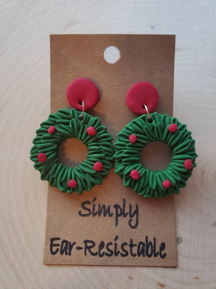 a pair of green and red earrings sitting on top of a cardboard card with the words simply ear - resistant