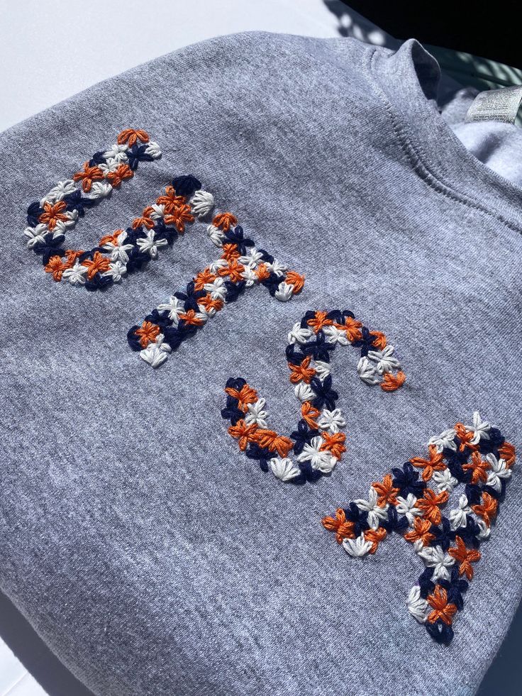 an embroidered sweatshirt with the word love spelled out in orange, white and blue flowers