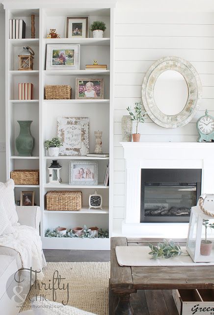 a living room filled with furniture and a fire place in front of a white bookcase