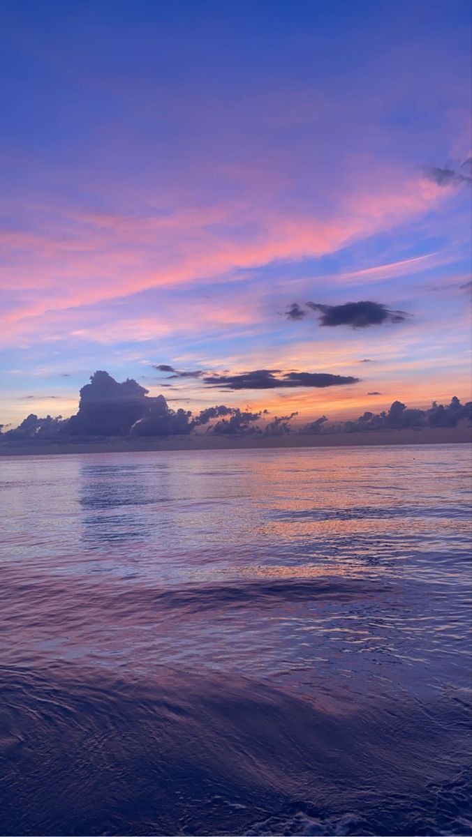 the sun is setting over the ocean with clouds in the sky and water below it