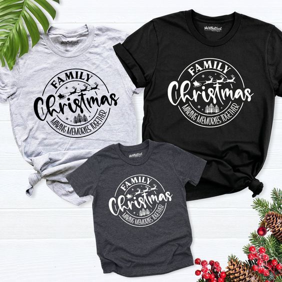 three family christmas t - shirts sitting on top of a white wooden table next to pine branches