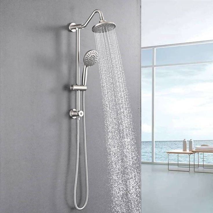 an open shower head with the water running down it's side and windows in the background