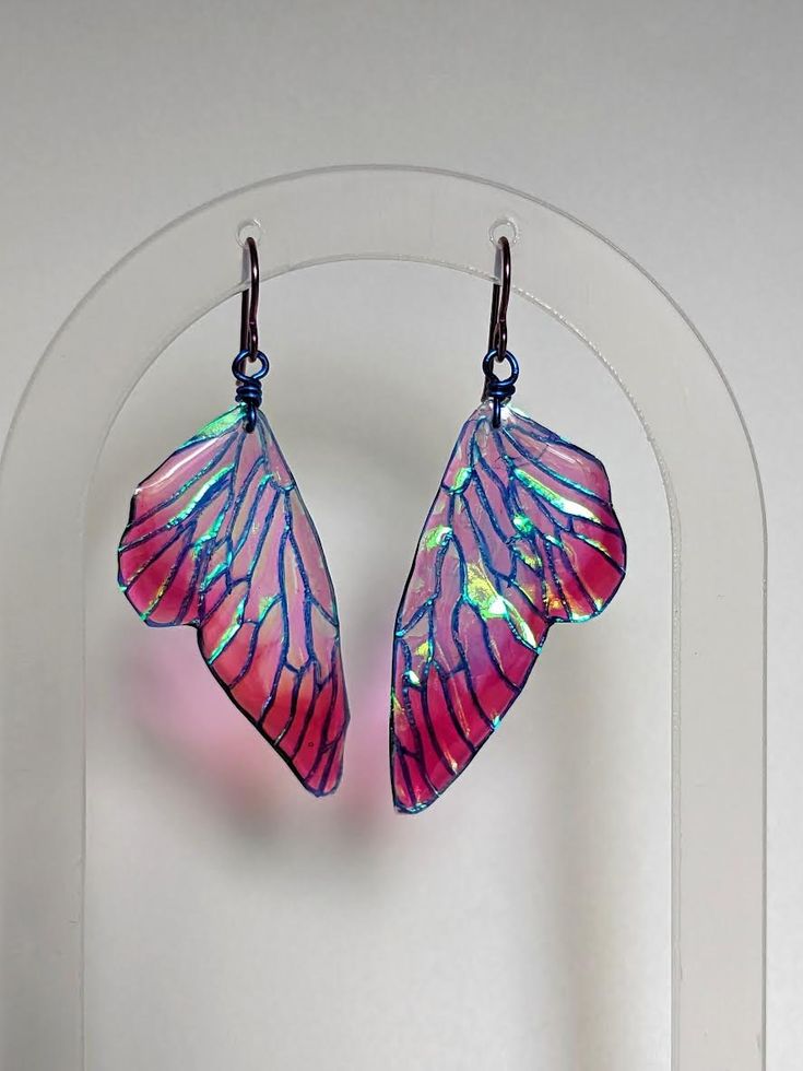 These Iridescent Pixie Wing Earrings are stunning and beautiful. To make these Fairy Wings, I start by creating a hand painted design. This design is then printed on transparent paper, and coated in layers of iridescent pigments. On all of my dangle earrings, I use hypoallergenic niobium ear hooks.  This material is pricier to work with, but safe for even the most sensitive ears. It has the added benefit of coming in beautiful colors, which are incorporated to become an integral design element. Unique Iridescent Earrings, Unique Iridescent Pierced Earrings, Fantasy Dangle Earrings For Festival, Fantasy Festival Dangle Earrings, Whimsical Adjustable Iridescent Jewelry, Handmade Iridescent Drop Earrings, Unique Iridescent Earrings For Party, Handmade Fairycore Earrings For Gift, Handmade Pink Fantasy Jewelry