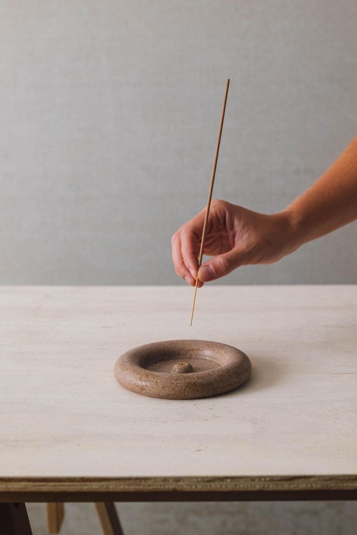 a person holding a stick over a small object on top of a table