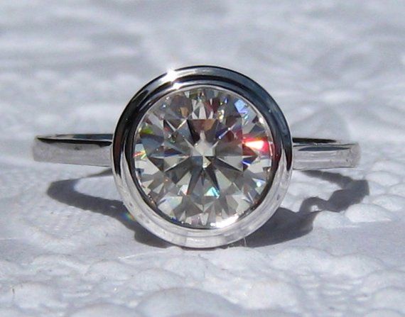 Here is an elegant and sparkly engagement ring, featuring a 2-carat Hearts & Arrows moissanite set in a sleek bezel solitaire mount. The center stone is probably most diamond-like moissanite I have seen! This is a limited edition moissanite that Charles & Colvard has cut into the Classic Moissanite Ring With Bezel Setting, Heirloom Moissanite Ring With Bezel Setting, Classic Bezel Set Promise Ring, Classic Moissanite Diamond Ring With Bezel Setting, Classic Wedding Ring With Bezel Setting, Classic Rings With Bezel Setting And Round Cut, Classic Bezel Set Diamond Promise Ring, Classic Cubic Zirconia Wedding Ring With Bezel Setting, Moissanite Bezels Wedding Ring For Anniversary