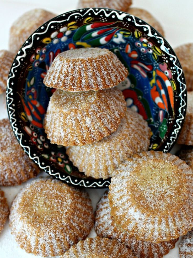 powdered sugar cookies stacked on top of each other in front of a plate full of them