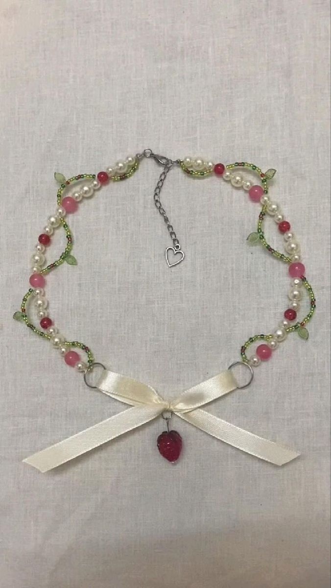 a necklace with pearls and a heart on the clasp is hanging from a white cloth