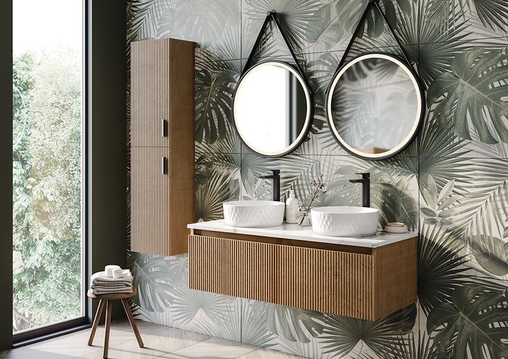 a bathroom with palm leaves on the wall and two round mirrors above the sinks,