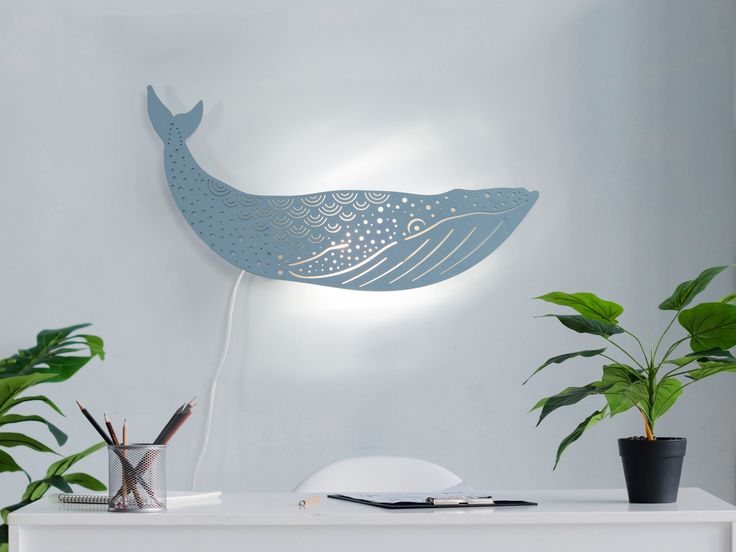 a blue whale lamp sitting on top of a white table next to potted plants