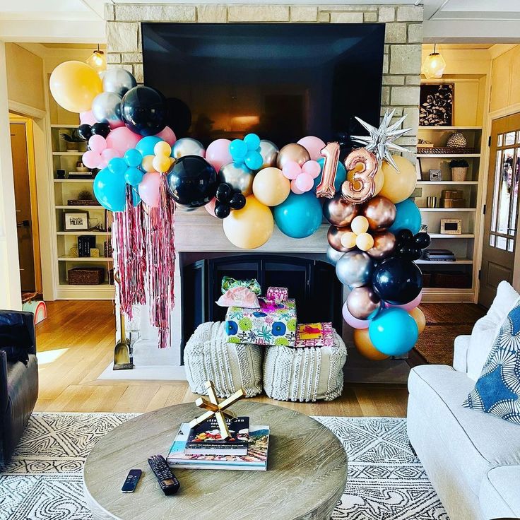 a living room filled with furniture and balloons hanging from the ceiling above a fire place