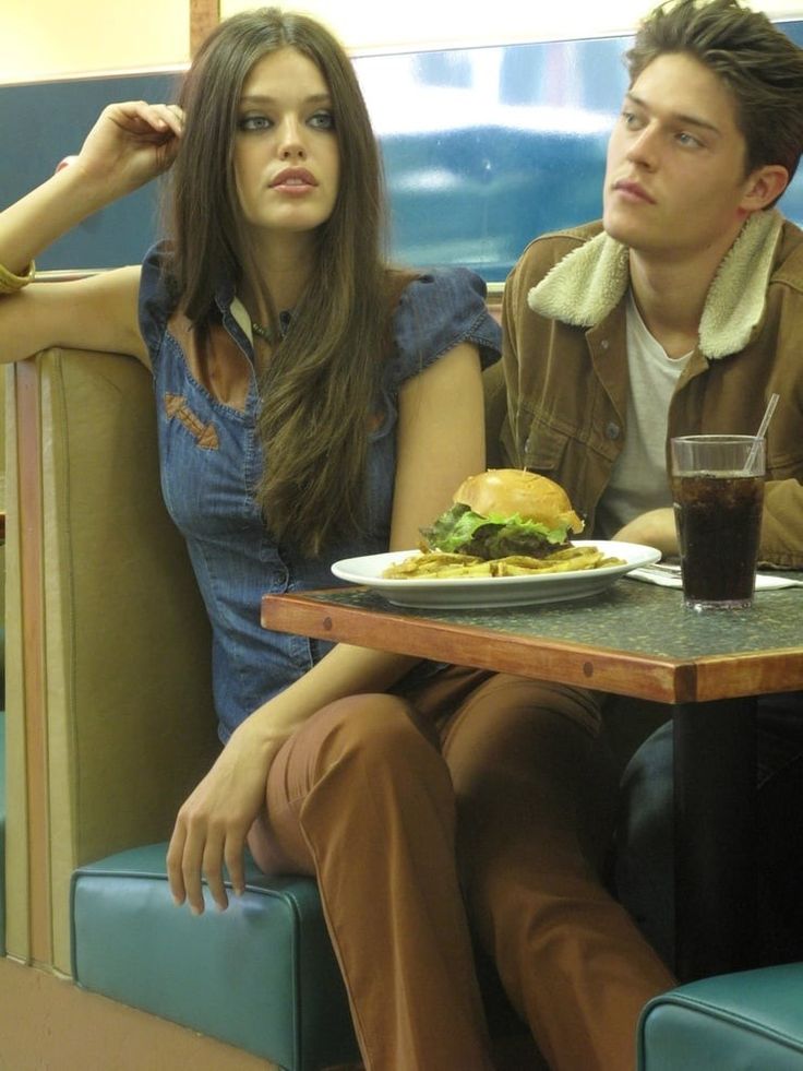 a man and woman sitting at a table with food