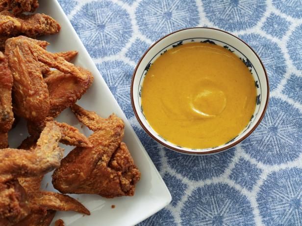 some fried food is on a plate next to a bowl of mustard and dipping sauce