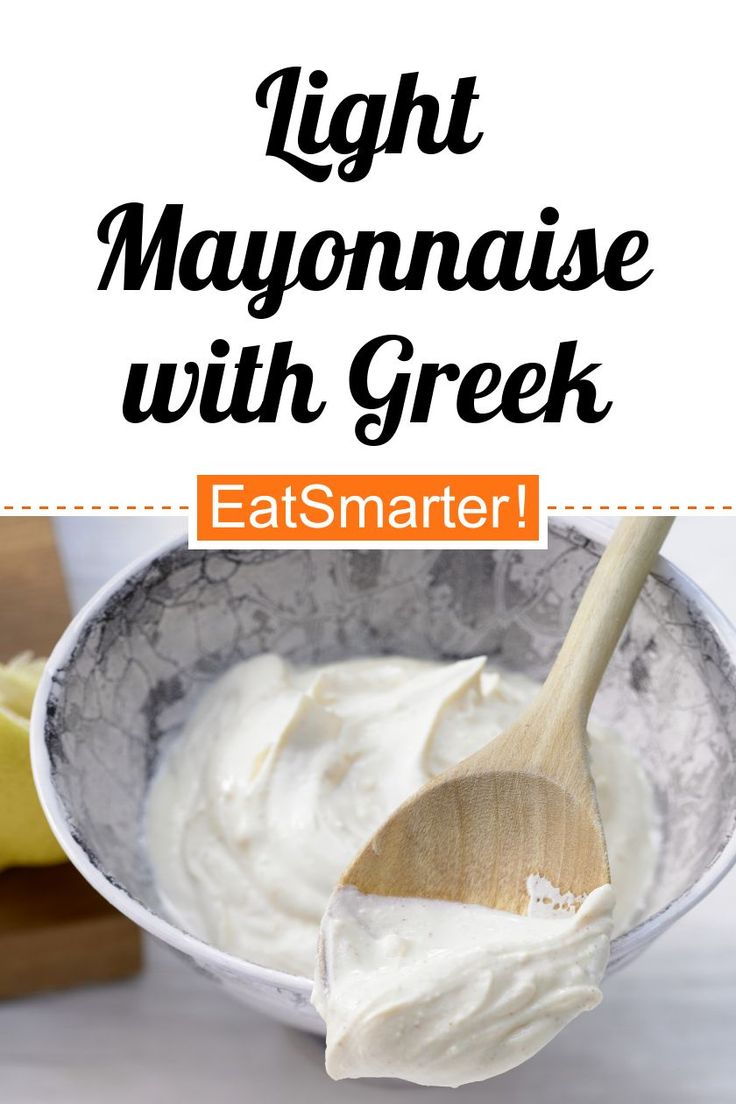 a bowl filled with mayonnaise next to a wooden spoon