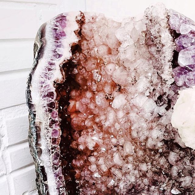 a large piece of ice with some white stuff on it's surface, sitting in front of a brick wall