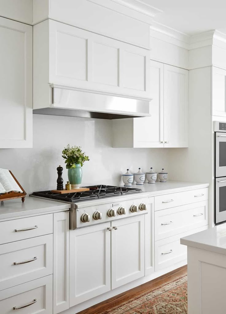 a white kitchen with an oven, stove and counter top area in it's center