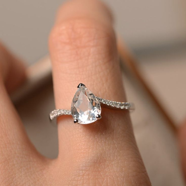 a woman's hand with a diamond ring on top of her finger and an engagement band